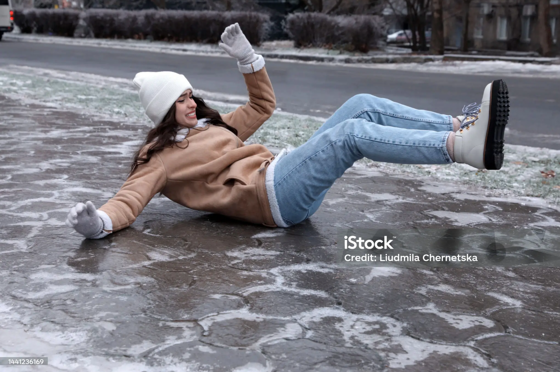 Woman losing balance while slipping on an icy sidewalk.