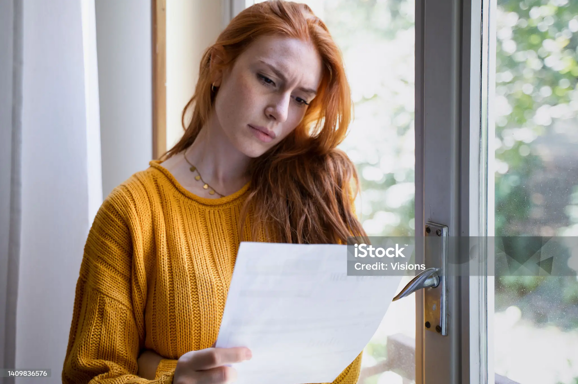 Woman reading a disability claim denial letter, considering next steps.