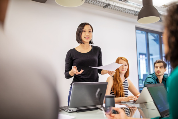 HR employee standing up and reviewing workplace policies with other employees.