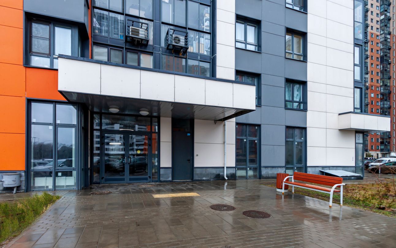The outside entrance of an apartment building depicts a wet pavement, posing a risk of an injury fro
