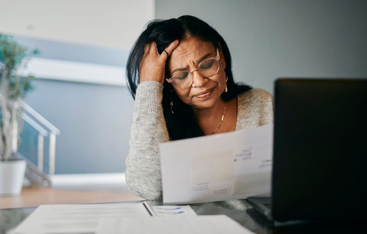 A concerned woman reviews a denied long-term disability claim letter at her desk with documents.