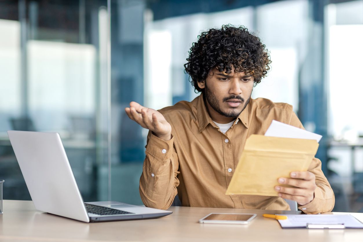 A person sitting at a desk, looking confused while reviewing a document, symbolizing uncertainty during the car accident settlement process.