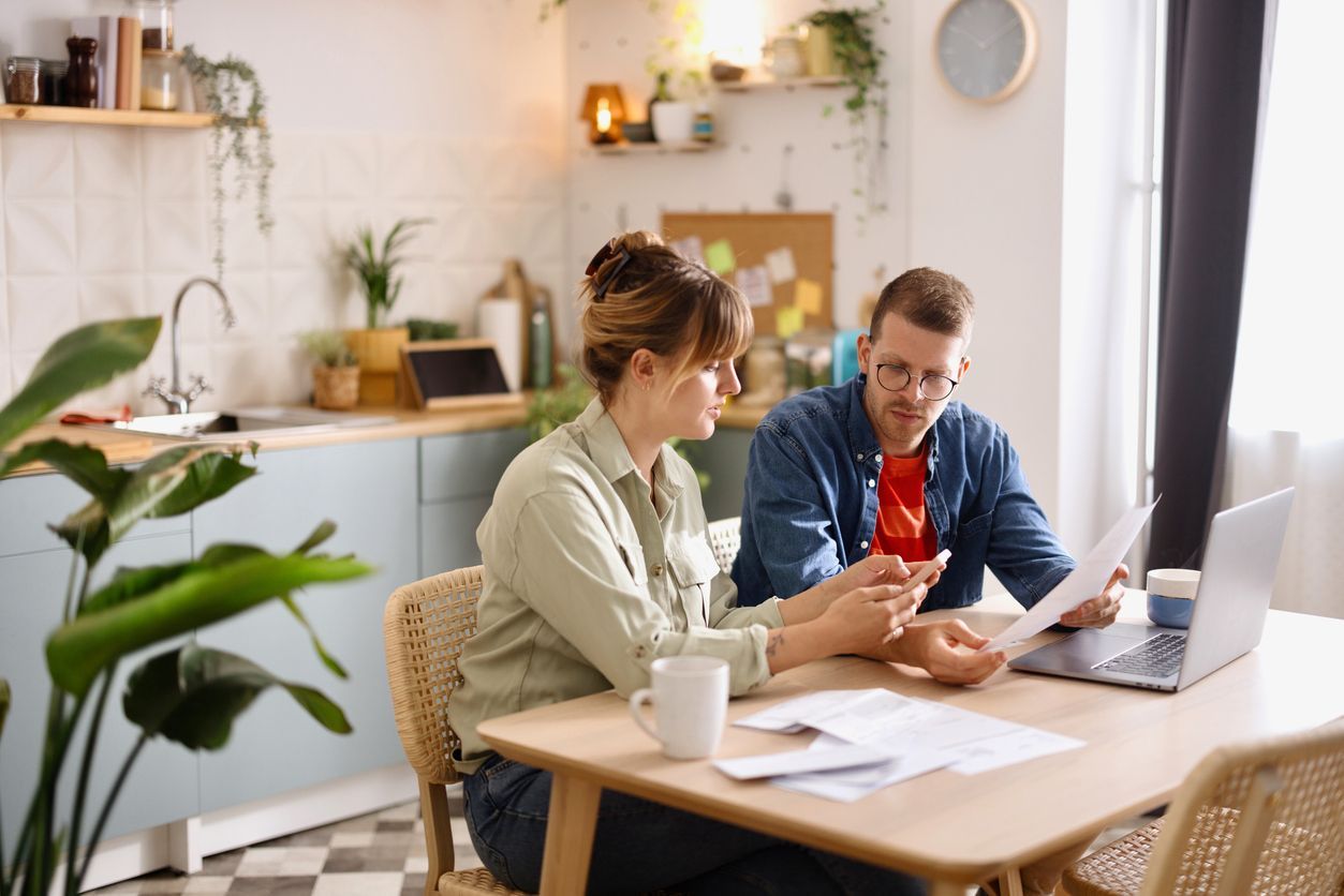 A couple sitting at the kitchen table reviews paperwork and discusses disability benefits termination, illustrating a scenario where a long-term disability lawyer can help.