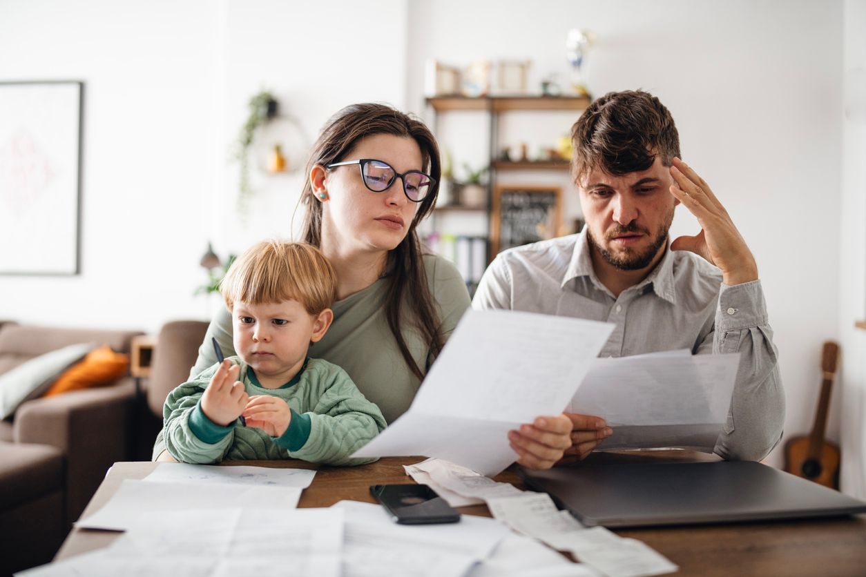 A young grieving family reviews life insurance paperwork at home after a loved one’s death.
