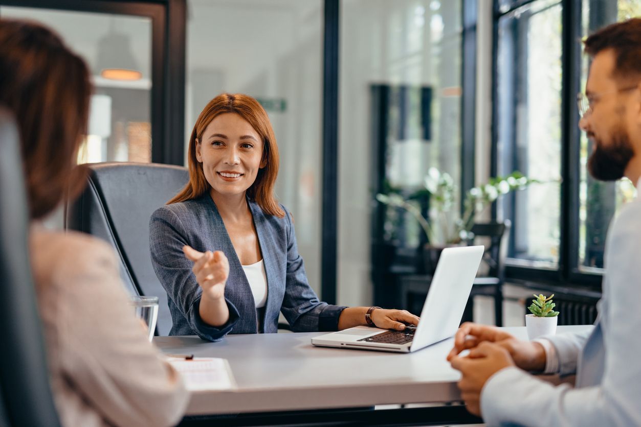 A long-term disability lawyer speaks with two clients at a desk in an office setting, discussing a denied long-term disability claim.