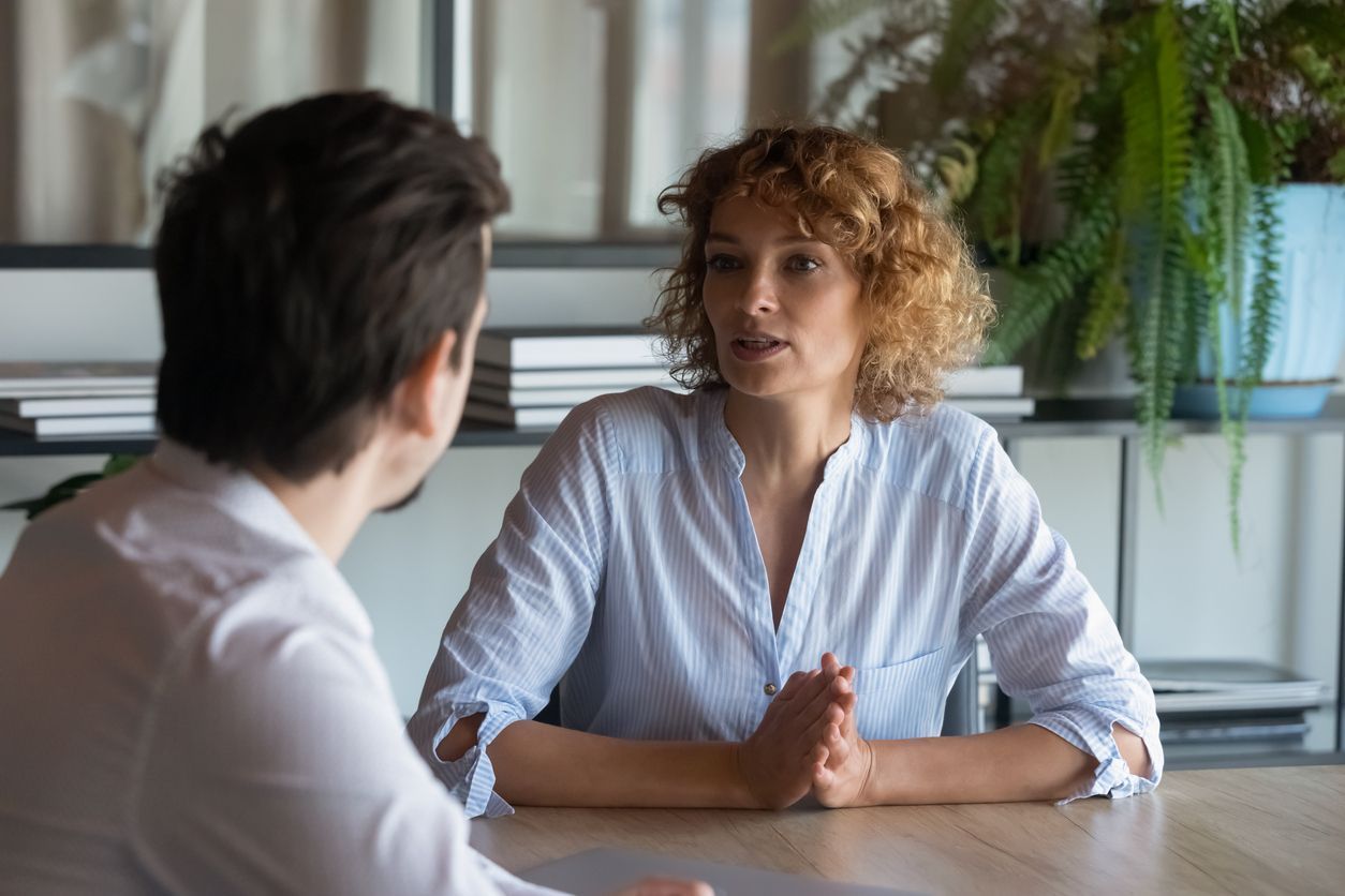 A female manager, sitting at a desk in an office setting, places an employee on temporary layoff, an example where an employment lawyer can offer guidance to the employee.