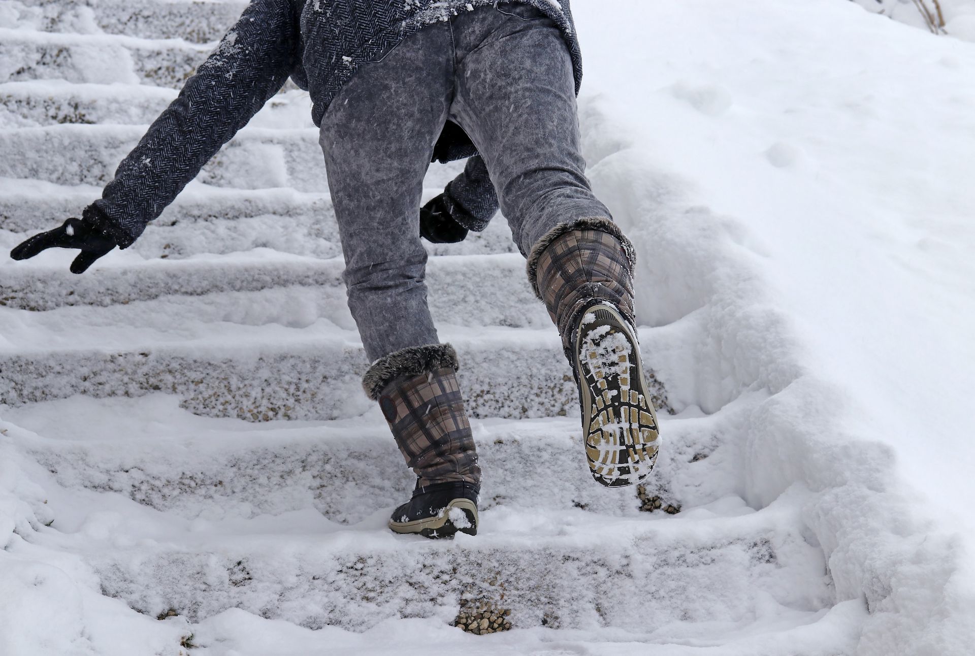 A person slipping on icy stairs, illustrating the hazards of unsafe conditions on private property.