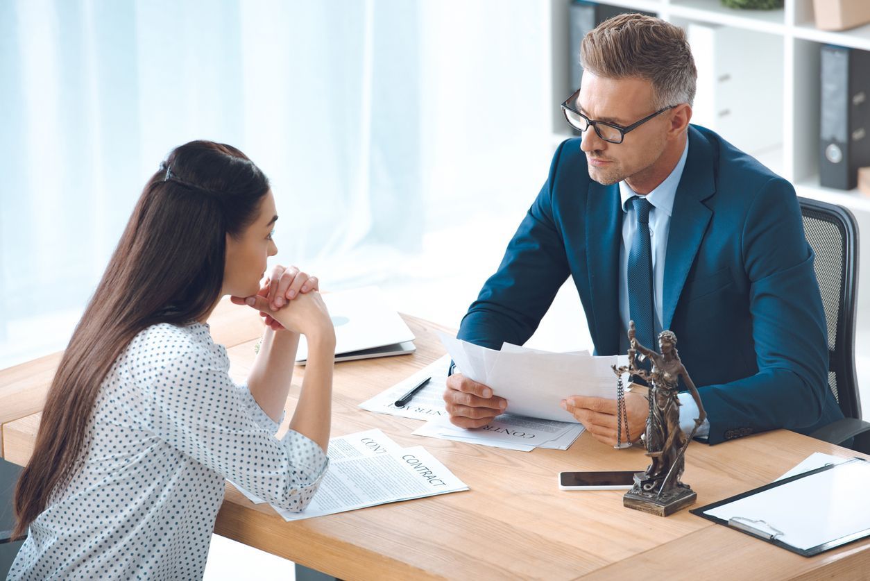 A lawyer consulting with a client at a desk, discussing legal documents and strategies for a slip and fall lawsuit.