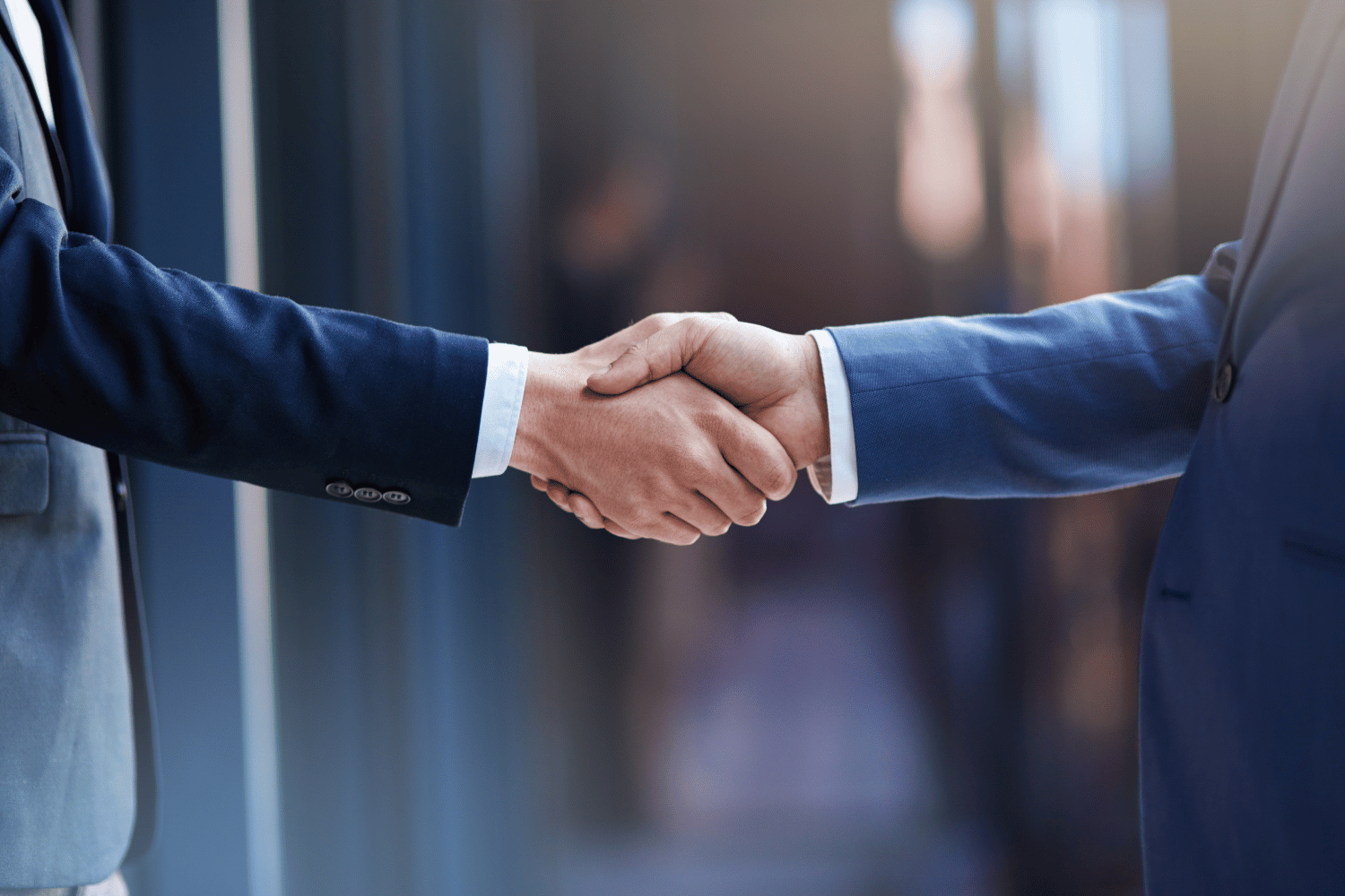 Two people in business suits shaking hands in an office setting