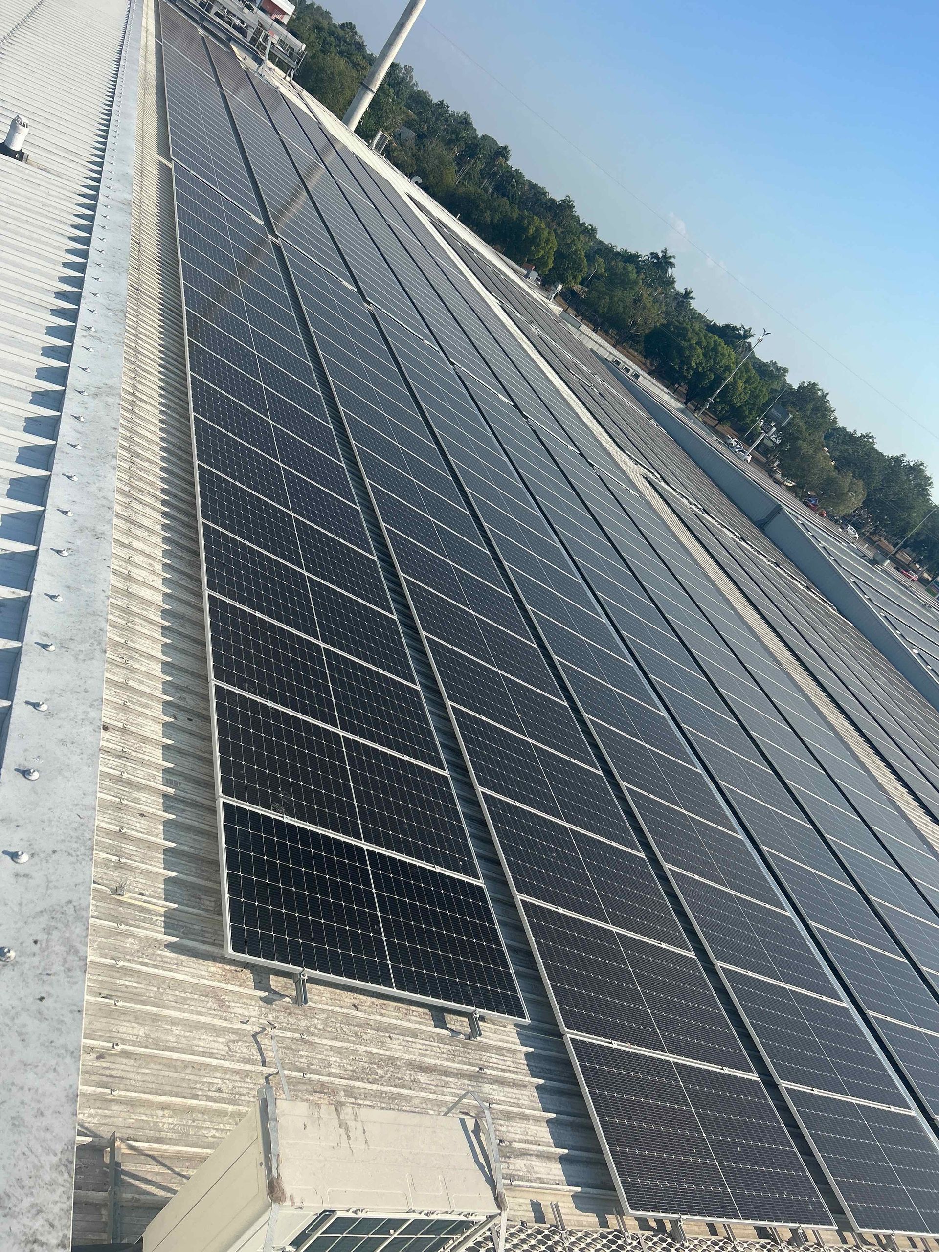 A Man Is Installing Solar Panels on The Roof of A Building — Eco Sparks Solar & Electrical Contractors in Berrimah, NT