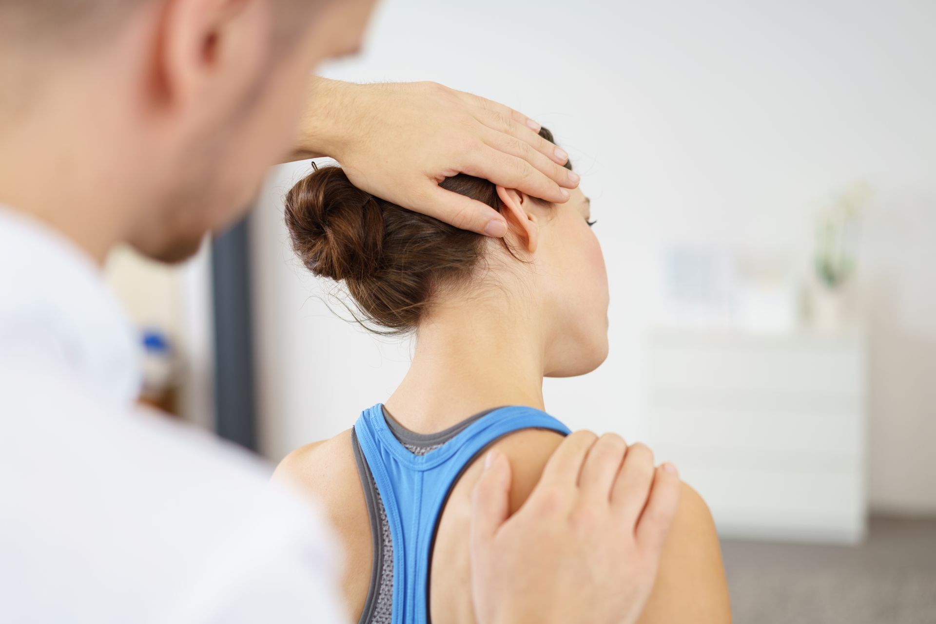 Close up Male Physical Therapist Stretching the Injured Neck of a Female Patient Slowly.