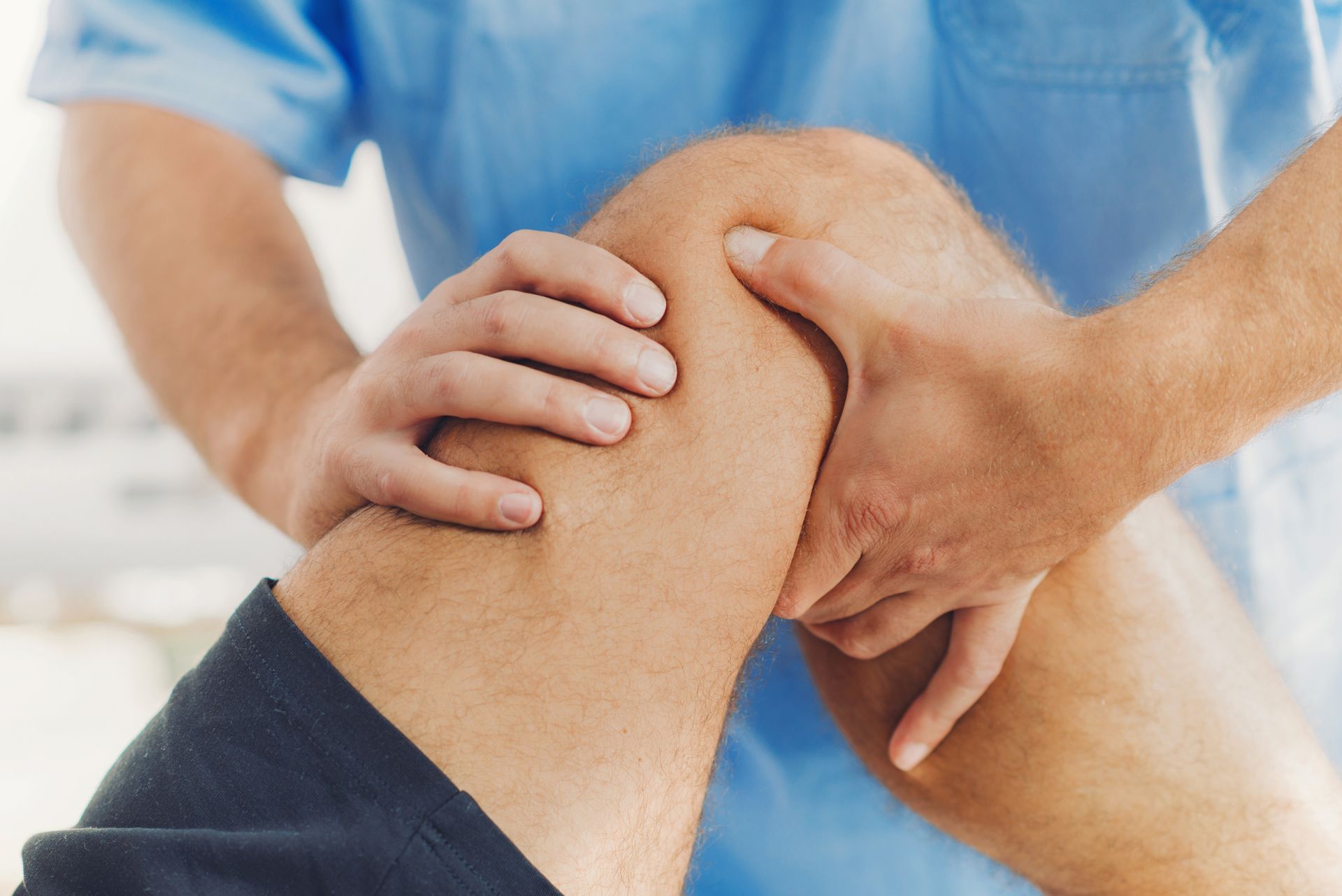 Physiotherapist doing healing treatment on patient leg. Therapist wearing blue uniform. Osteopathy, Chiropractic leg adjustment.