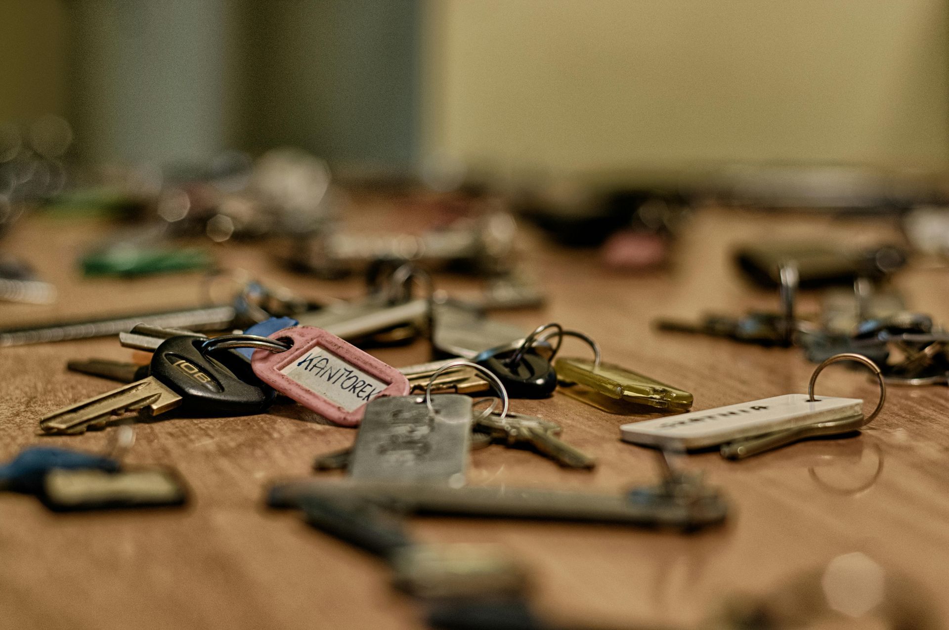 A bunch of keys are laying on a wooden table.
