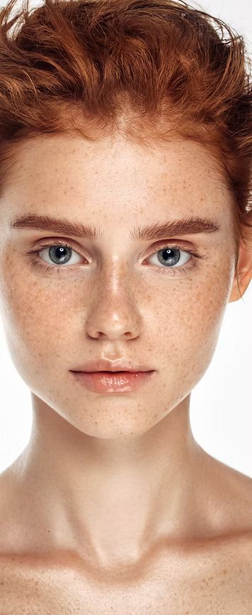Nahaufnahme einer Person mit roten Haaren und Sommersprossen, die den Betrachter direkt ansieht.