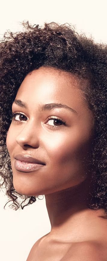 Frau mit lockigem Haar blickt mit einem leichten Lächeln nach links.