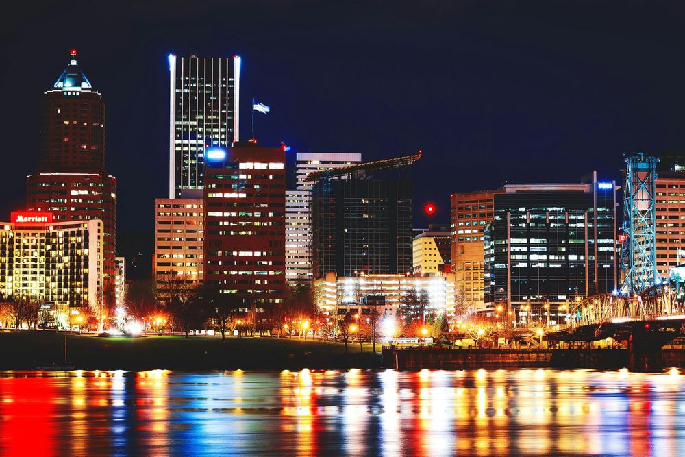 A city skyline at night with a river in the foreground