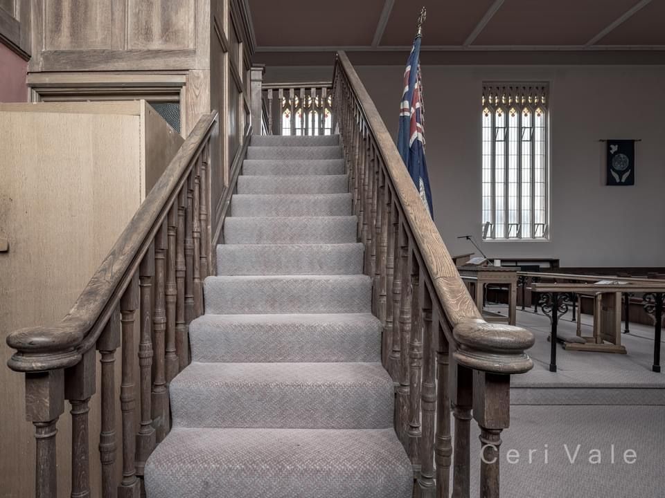 A staircase with a wooden railing and a british flag
