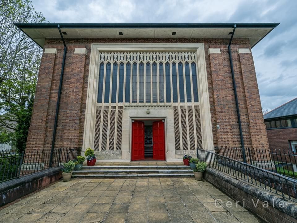 The front of a brick building with a red door