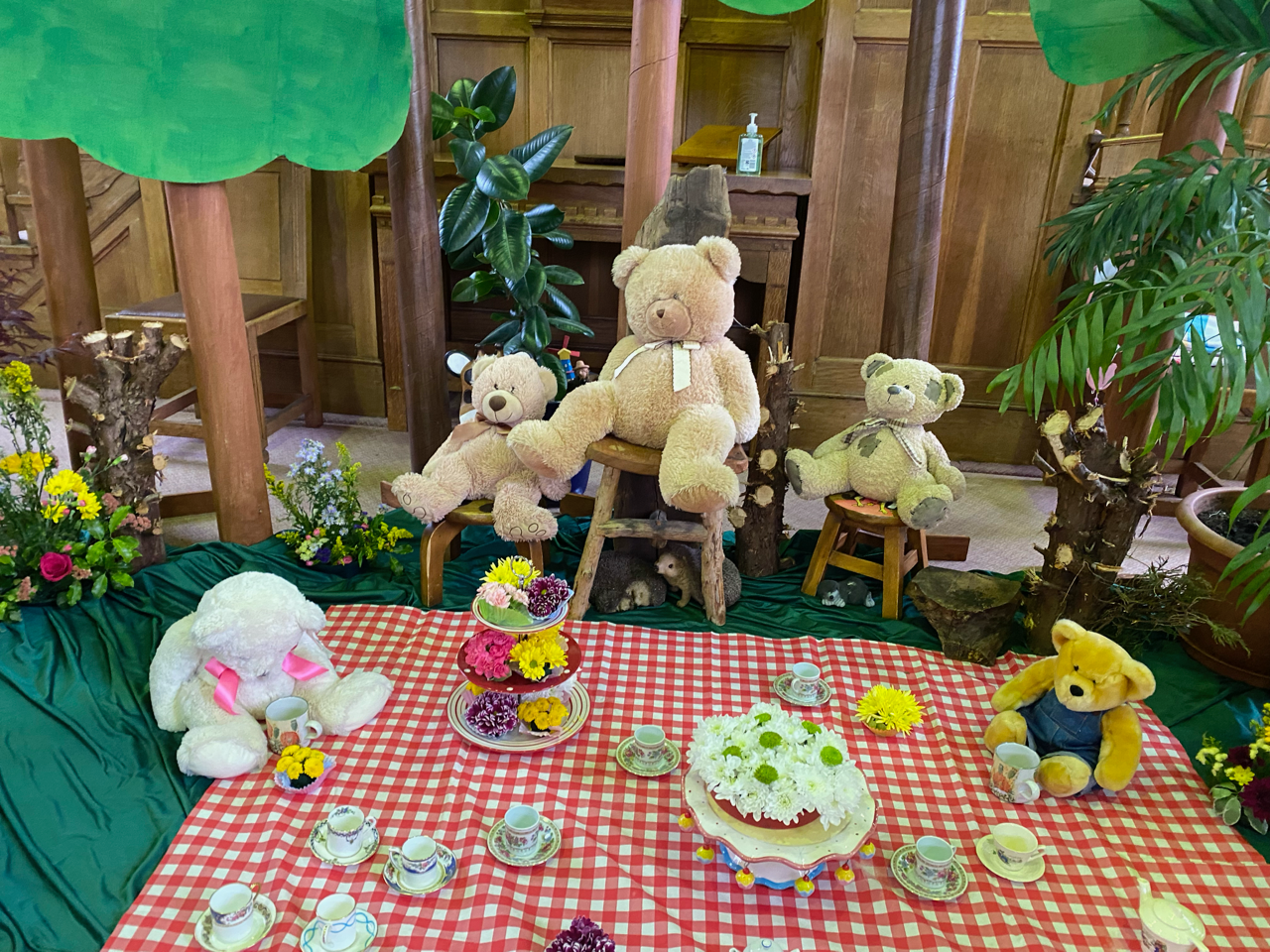 Three teddy bears are sitting on a red and white checkered table