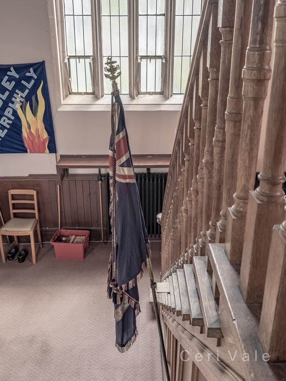 A flag is hanging from a pole in a room with stairs