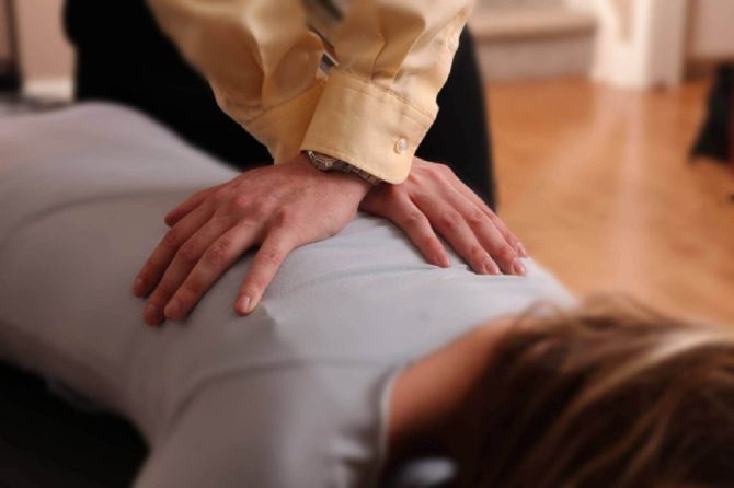 Hands pressing on a person’s back during a massage on a couch