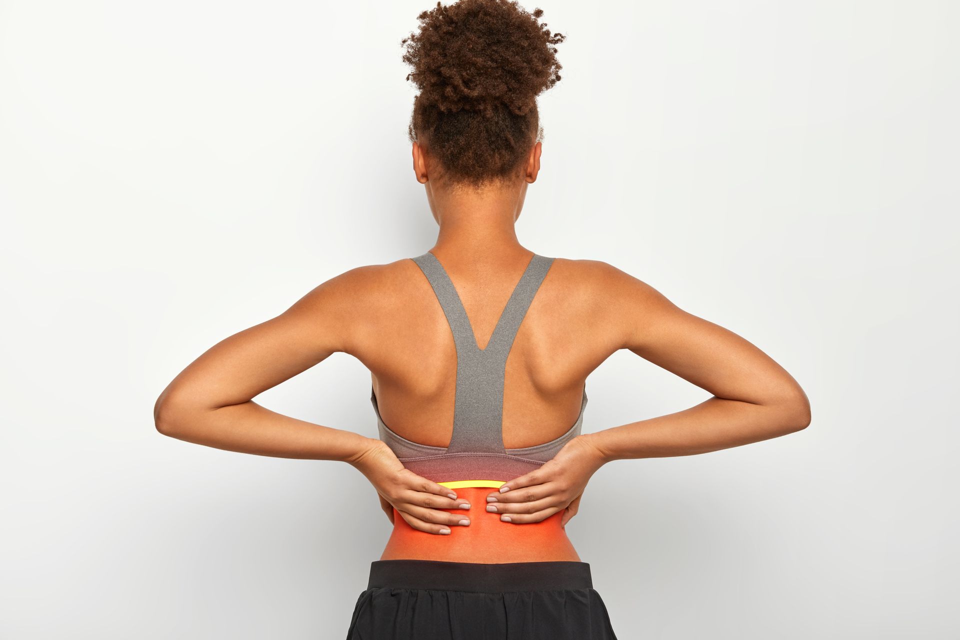 Person holding lower back in pain, showing highlighted pain area on back after workout