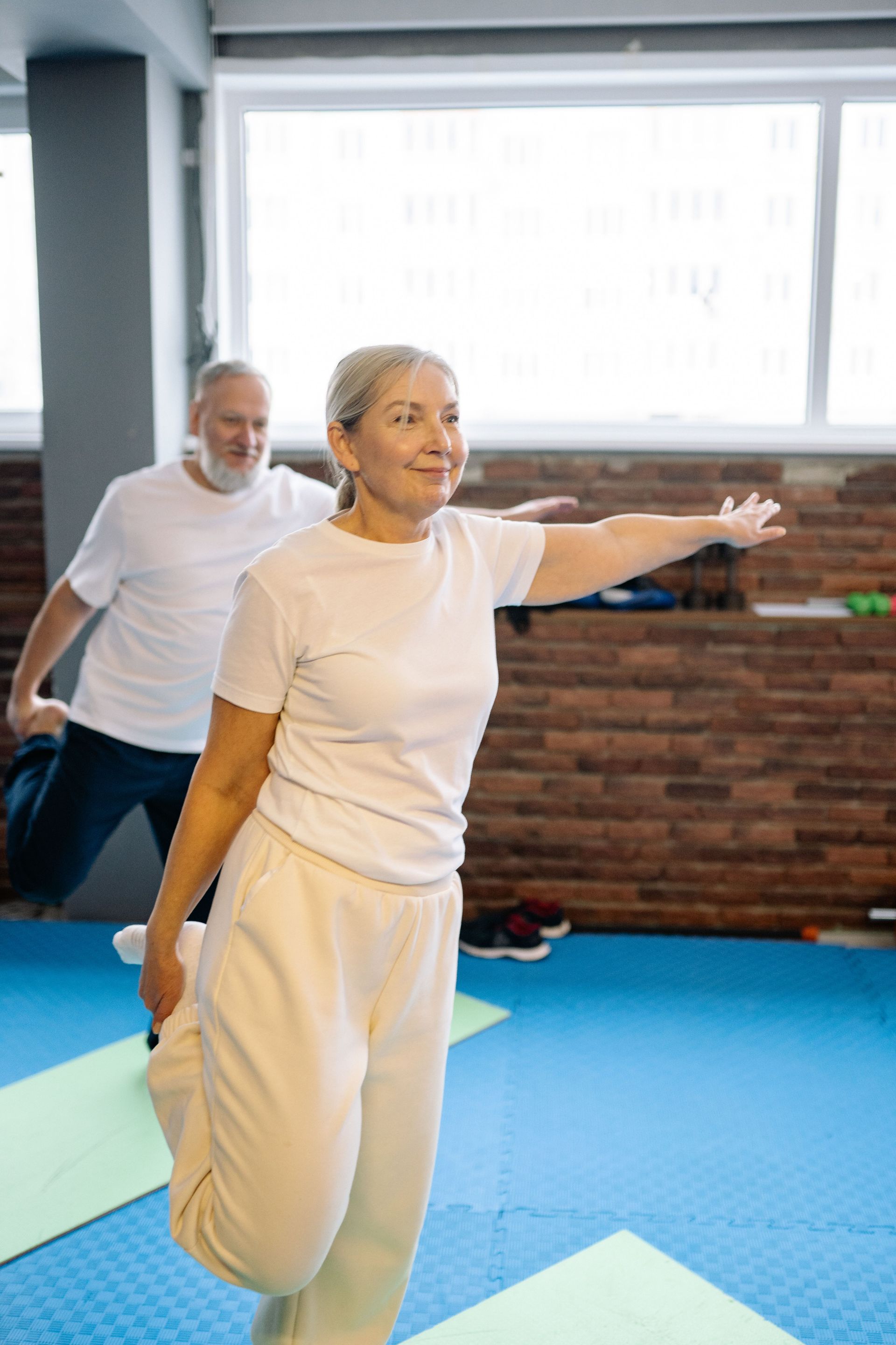 Two people stretching in a bright exercise studio on blue mats