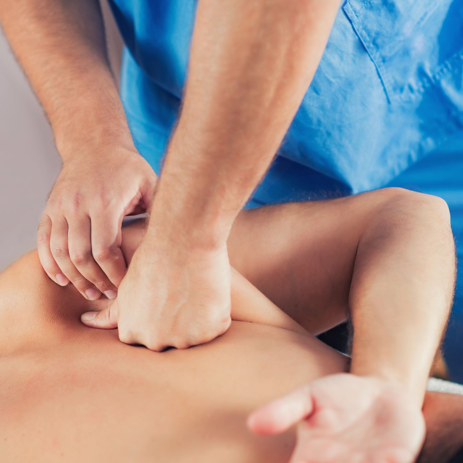 Hands performing a back massage on a person lying face down, with blue towels in the background.