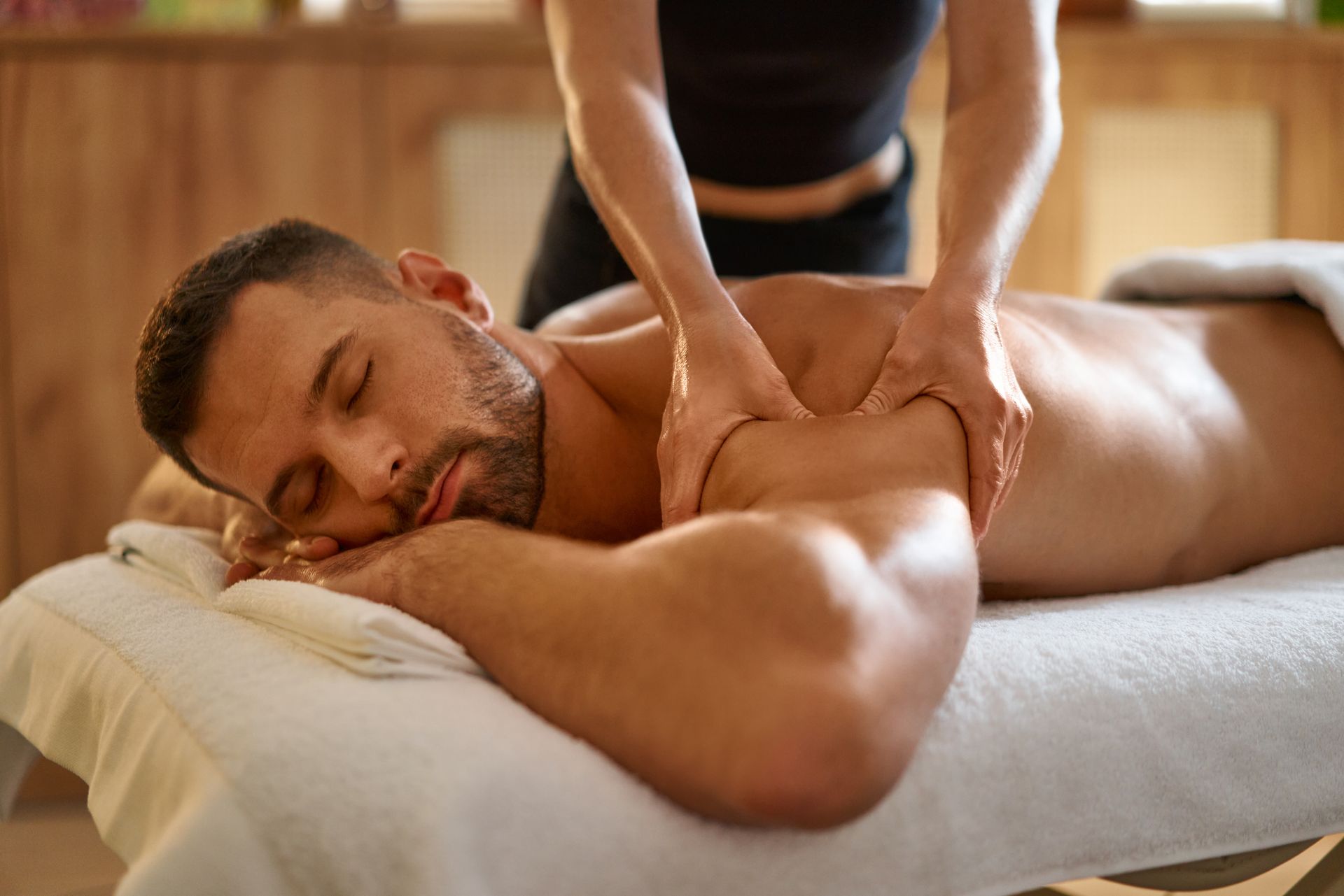 Man receiving a back massage on a treatment table in a warm spa setting