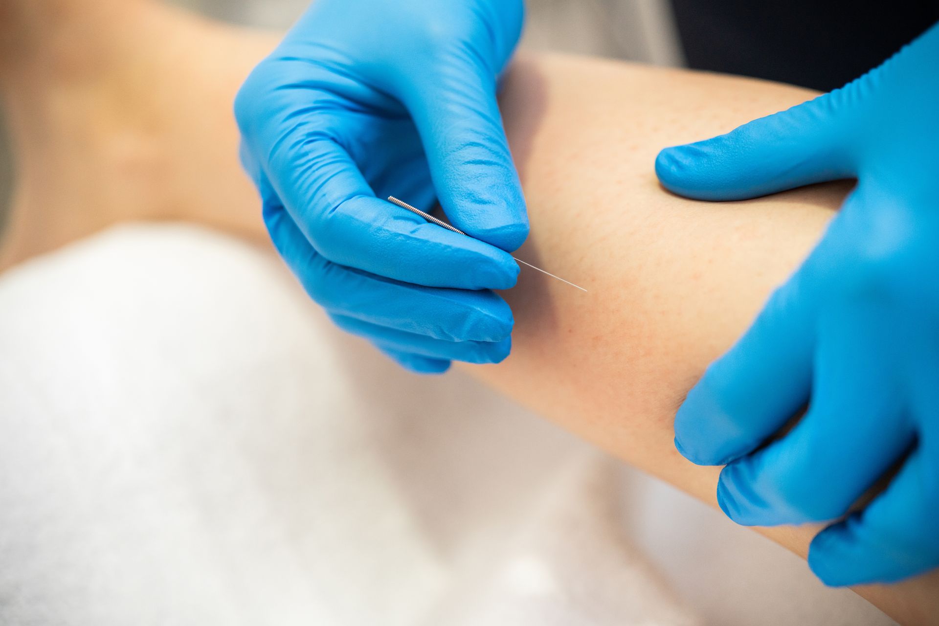Gloved hands giving an injection in a person’s arm with a syringe