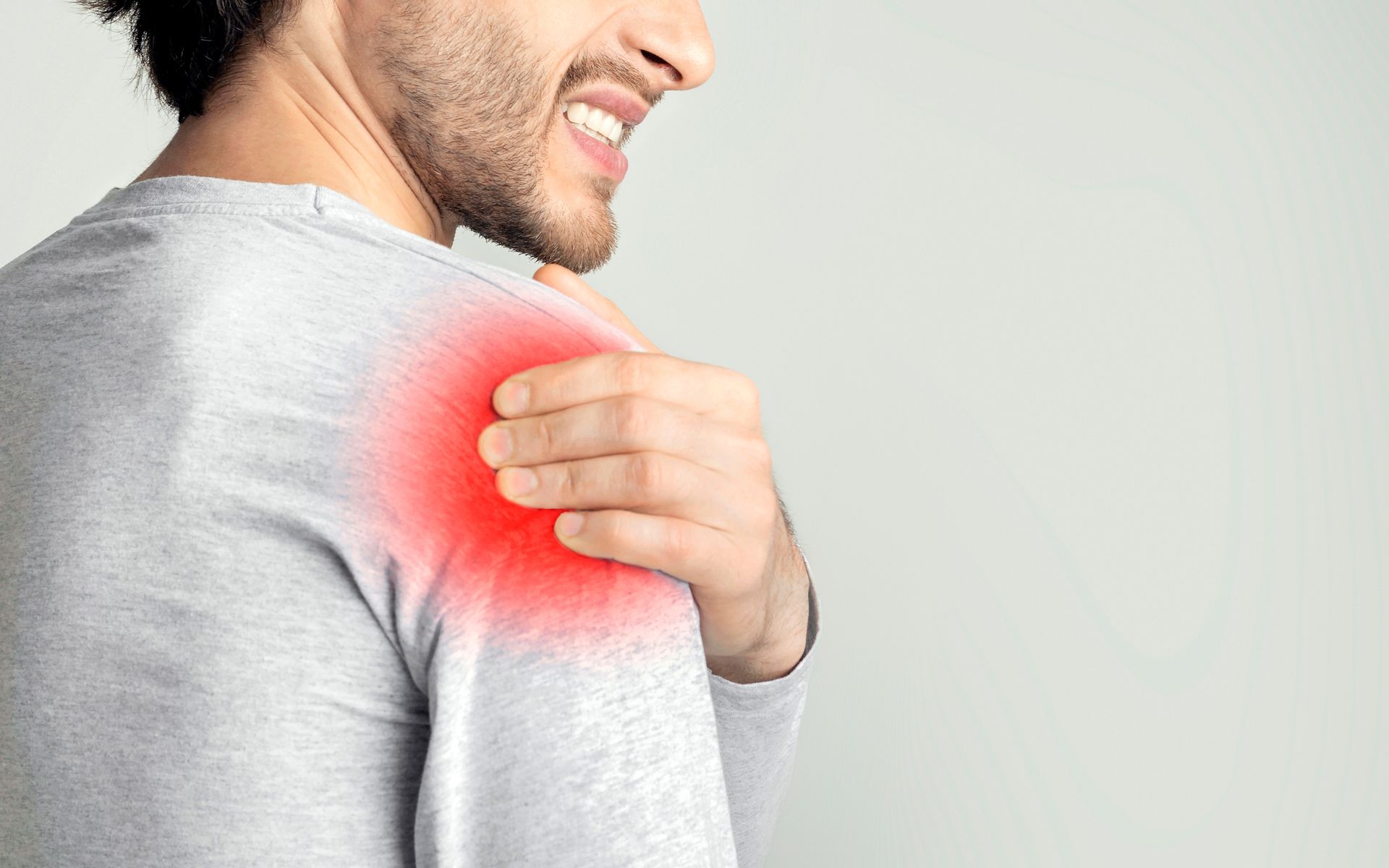 Man holding his shoulder with a red pain highlight, indicating shoulder pain