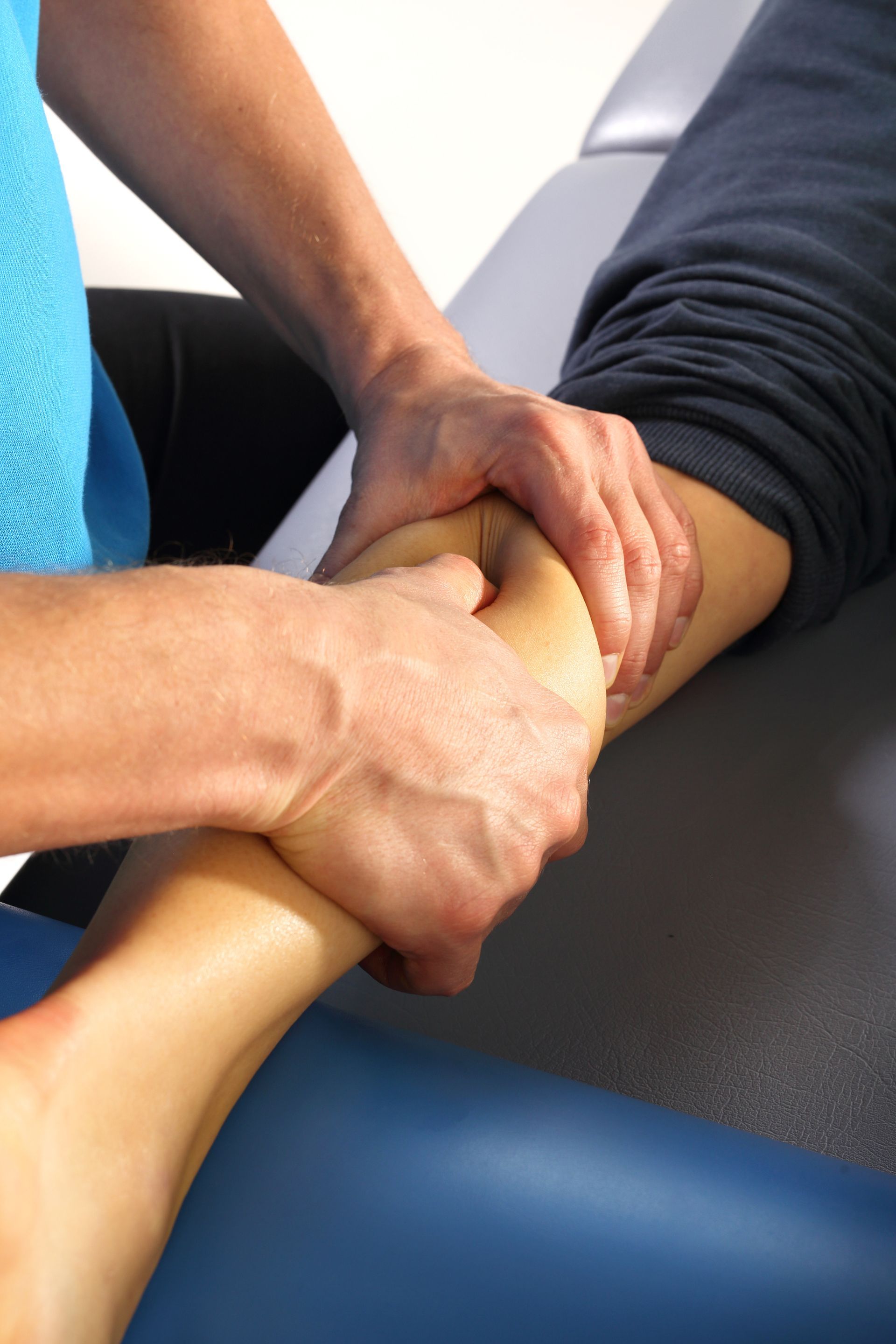 Hands massaging an ankle on a treatment table