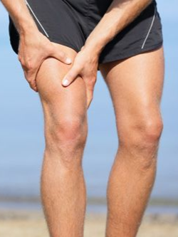 Person holding a painful knee on a beach