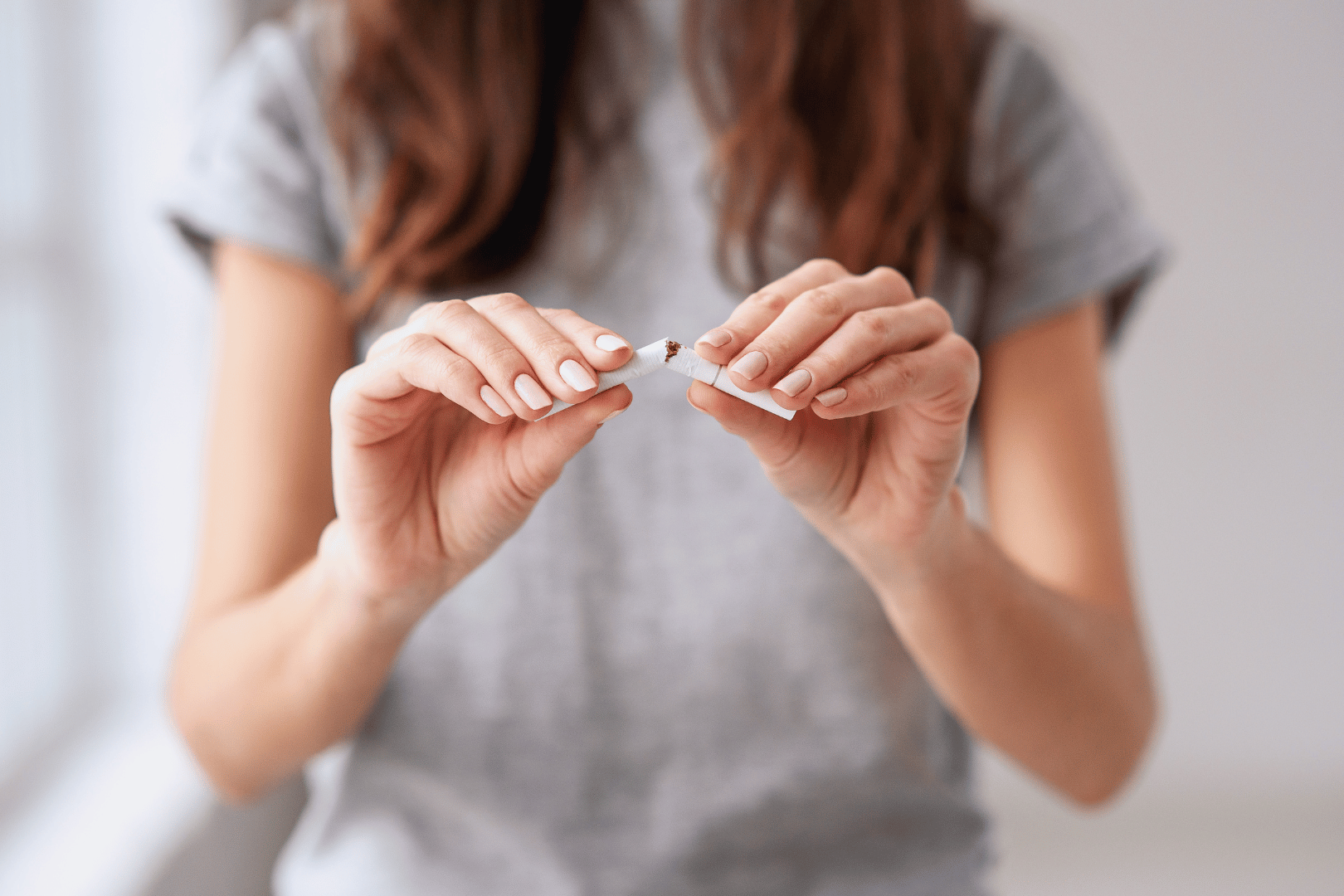 Woman breaking a cigarette in half with her hands.