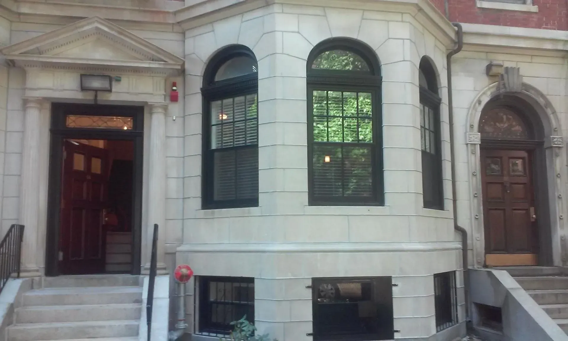 Exterior of a building with stone facade, arched windows and doorways, steps leading to entries.