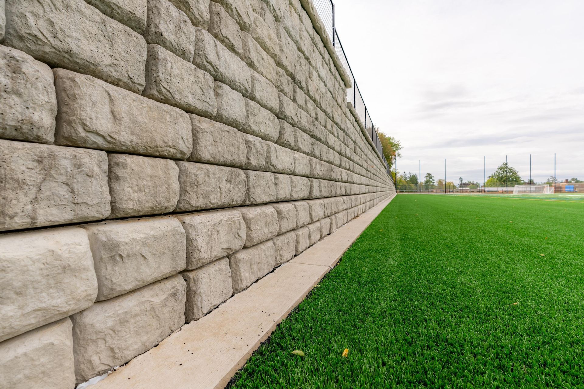 Stone retaining wall beside bright green lawn under an overcast sky
