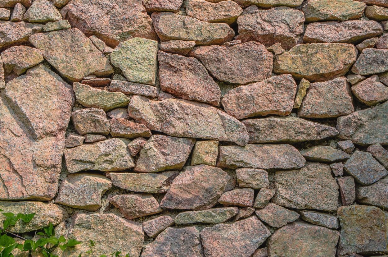 Stone wall with pink, gray, and tan granite rocks.