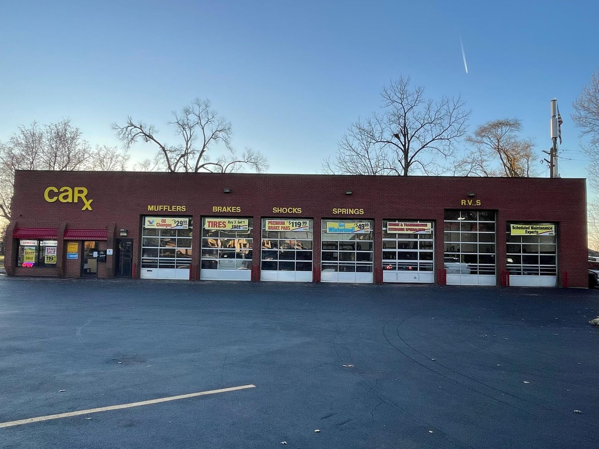 Car repair shop, CarX, with a dark brick building and multiple garage doors. Paved parking lot.