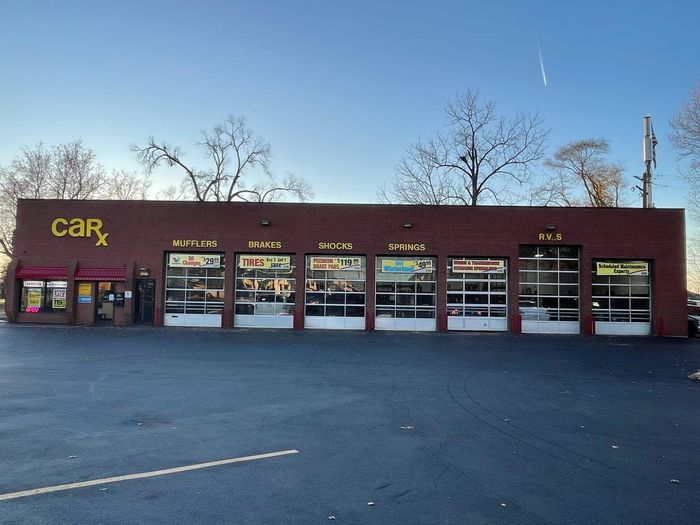 Car repair shop, CarX, with a dark brick building and multiple garage doors. Paved parking lot.