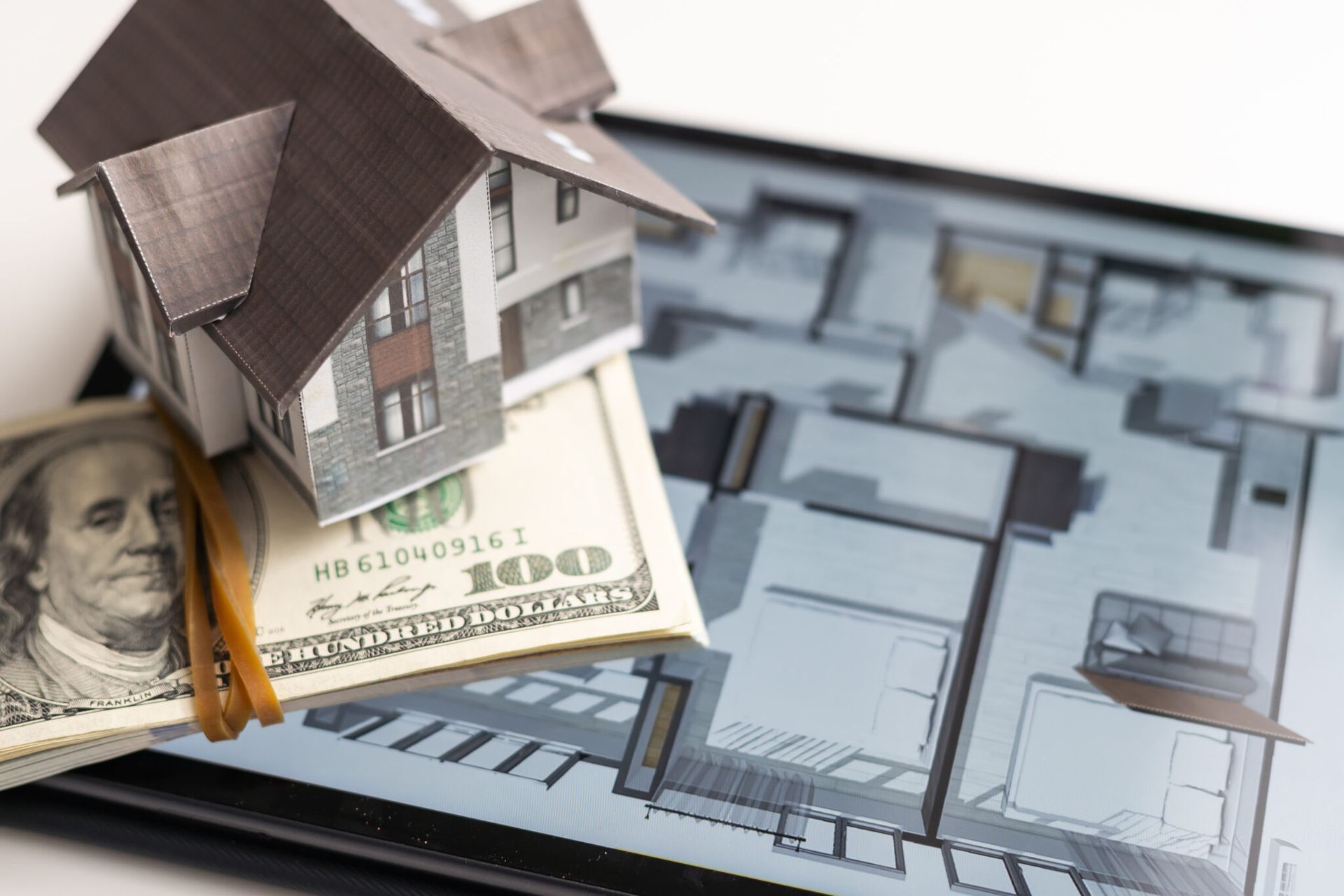 A model house is sitting on top of a stack of money.