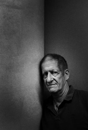 Professional Portrait by Stu Spence an elderly gentleman leading against the corner of a room in moody black and white