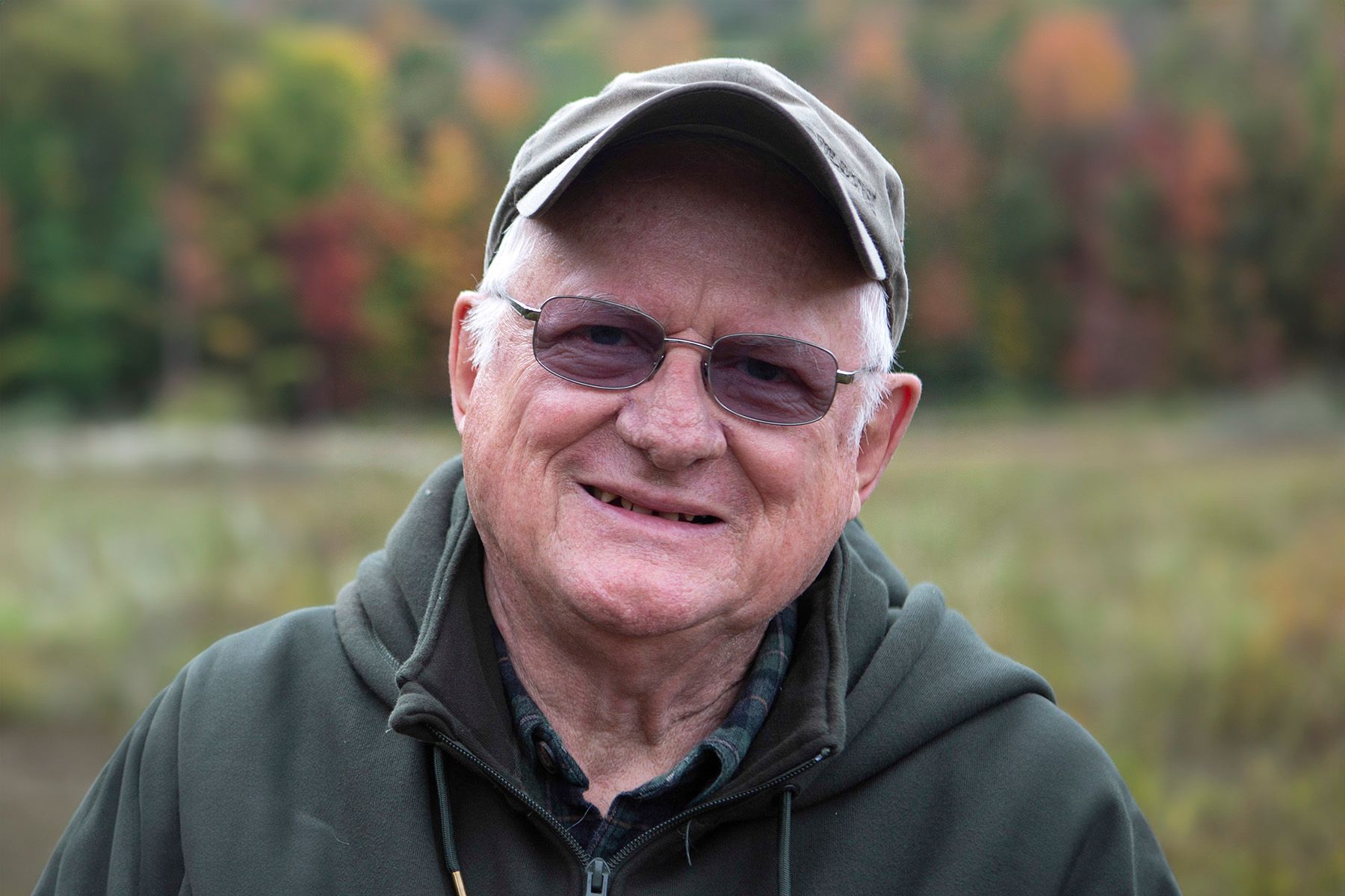 A man wearing a hat and sunglasses is smiling for the camera.