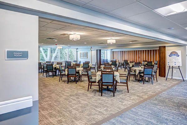 Dining room with tables, chairs, carpet, and three chandeliers.