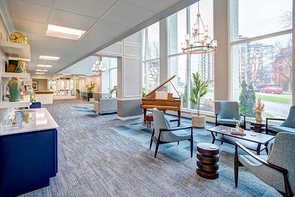 Elegant lobby with grand piano, seating, and large windows overlooking exterior. Blue and neutral tones.