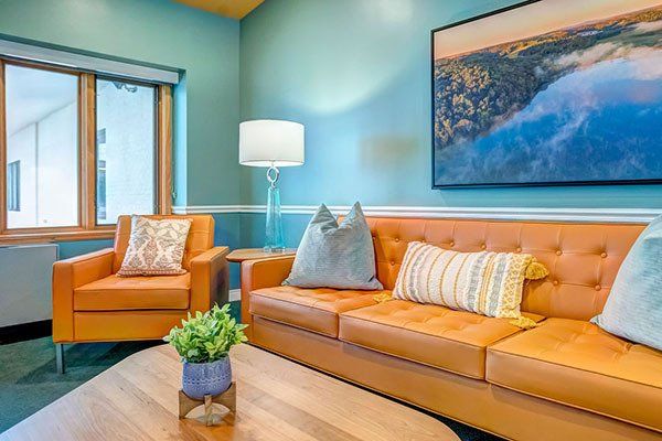 Living room with orange furniture, blue walls, and a large landscape painting.