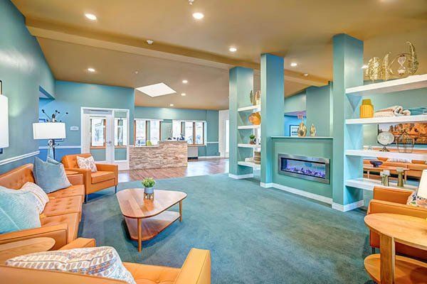 Bright lobby with teal walls, brown couches, fireplace, and reception desk.