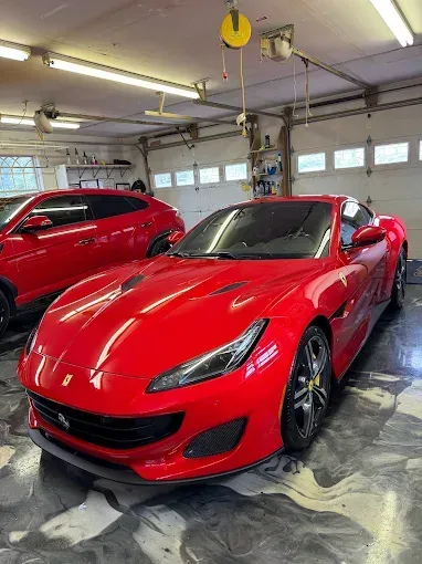 Red Ferrari sports car parked inside a garage next to a red SUV.