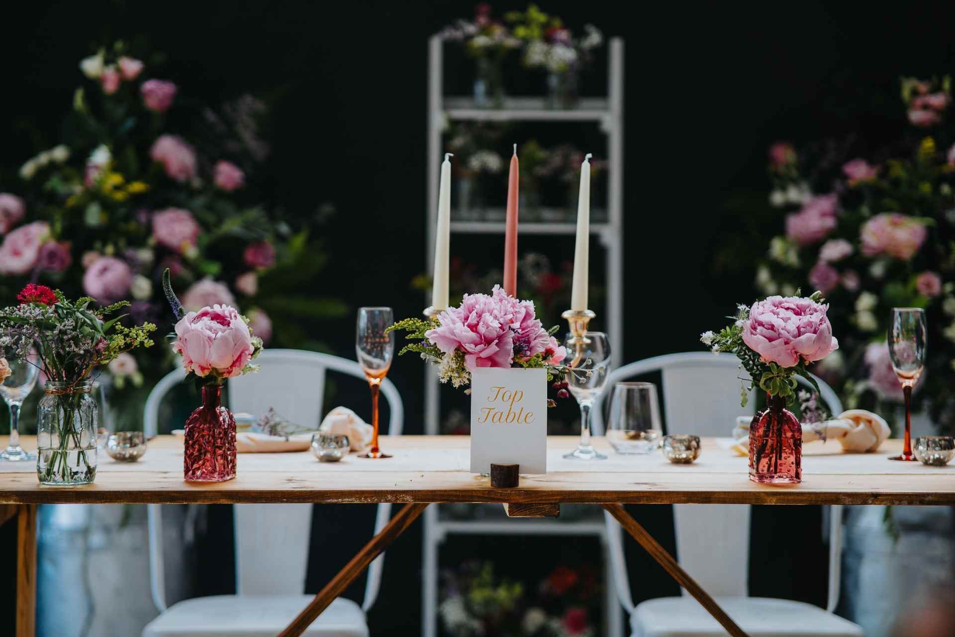 wedding set up with candles and rose tint glasses and wooden tables 