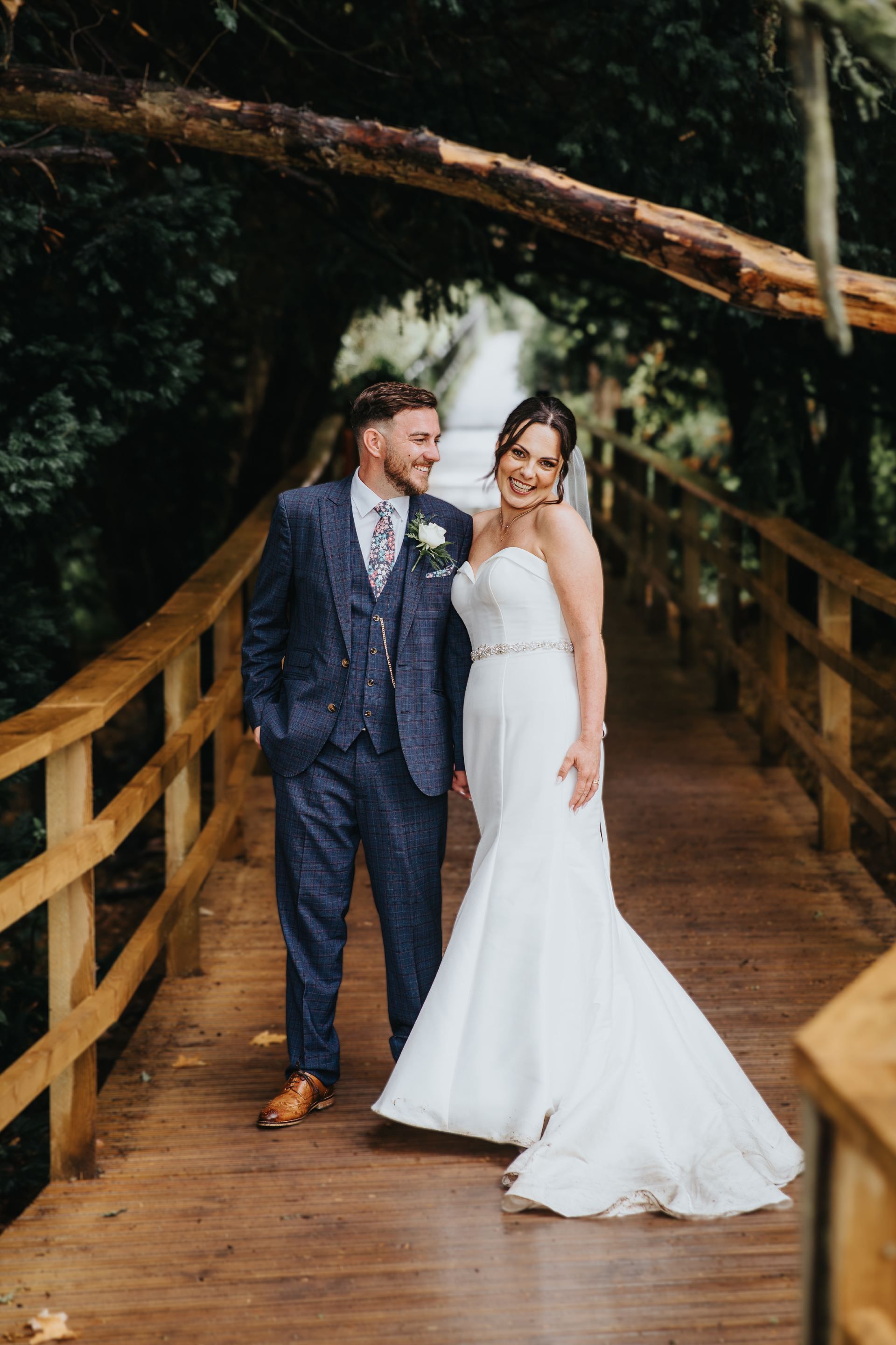 bride and groom walking across wooden bridge in warwickshire, Saxon mill 