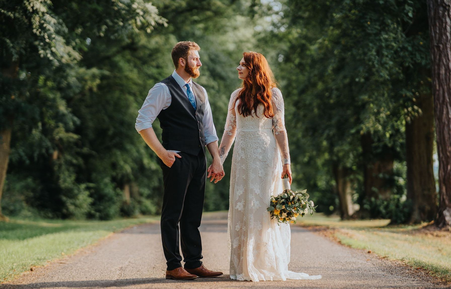 newly married couple portrait on long wooded road in Warwickshire 